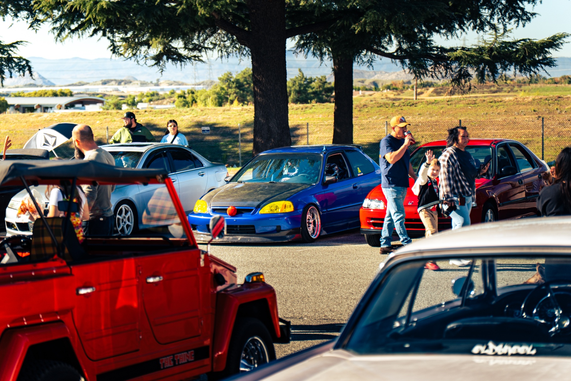 Crowd and colorful stanced cars packed into the Beaumont meet with mountain views